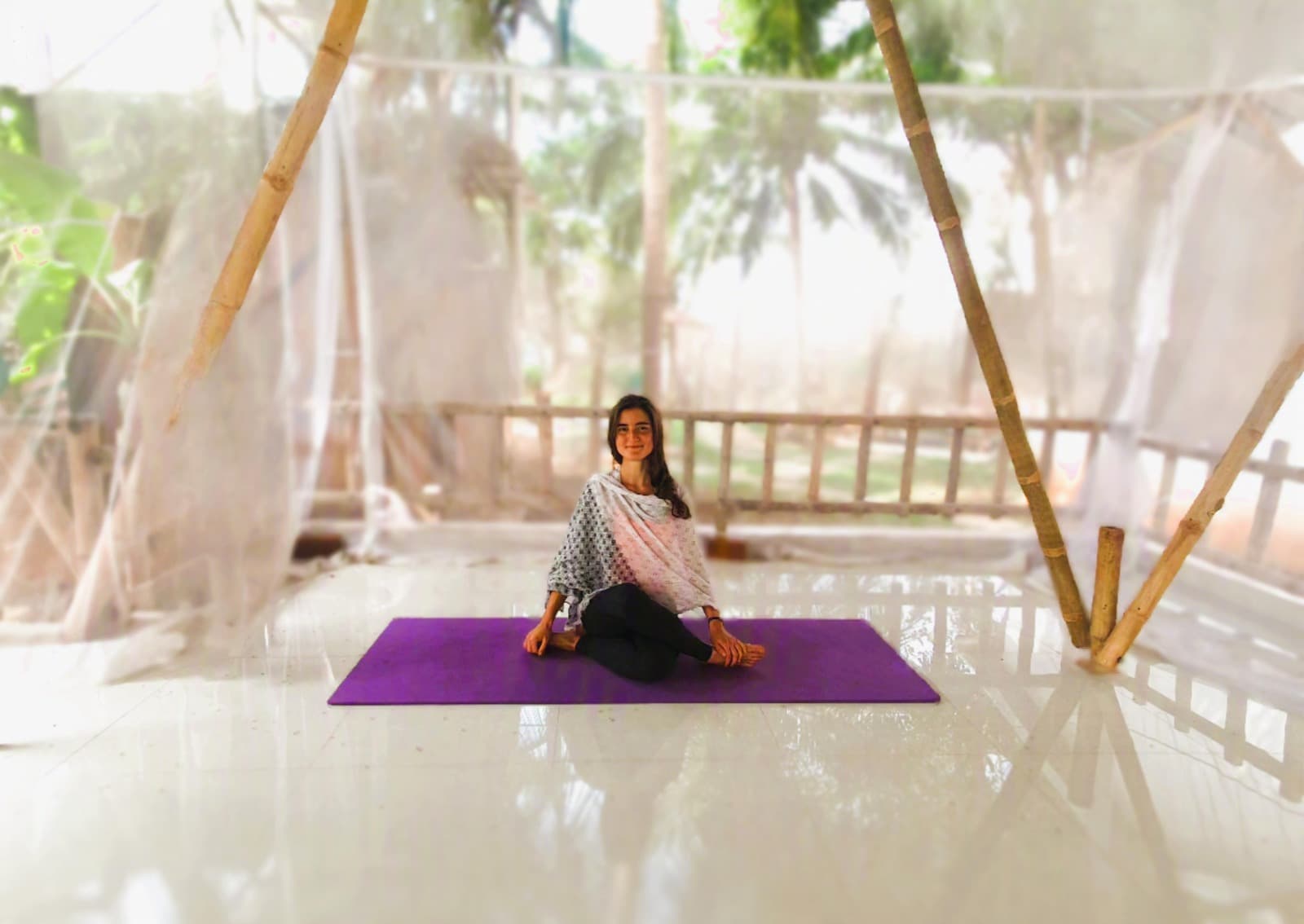 Camila, profesora de yoga, sentada en meditación en un pabellón de bambú